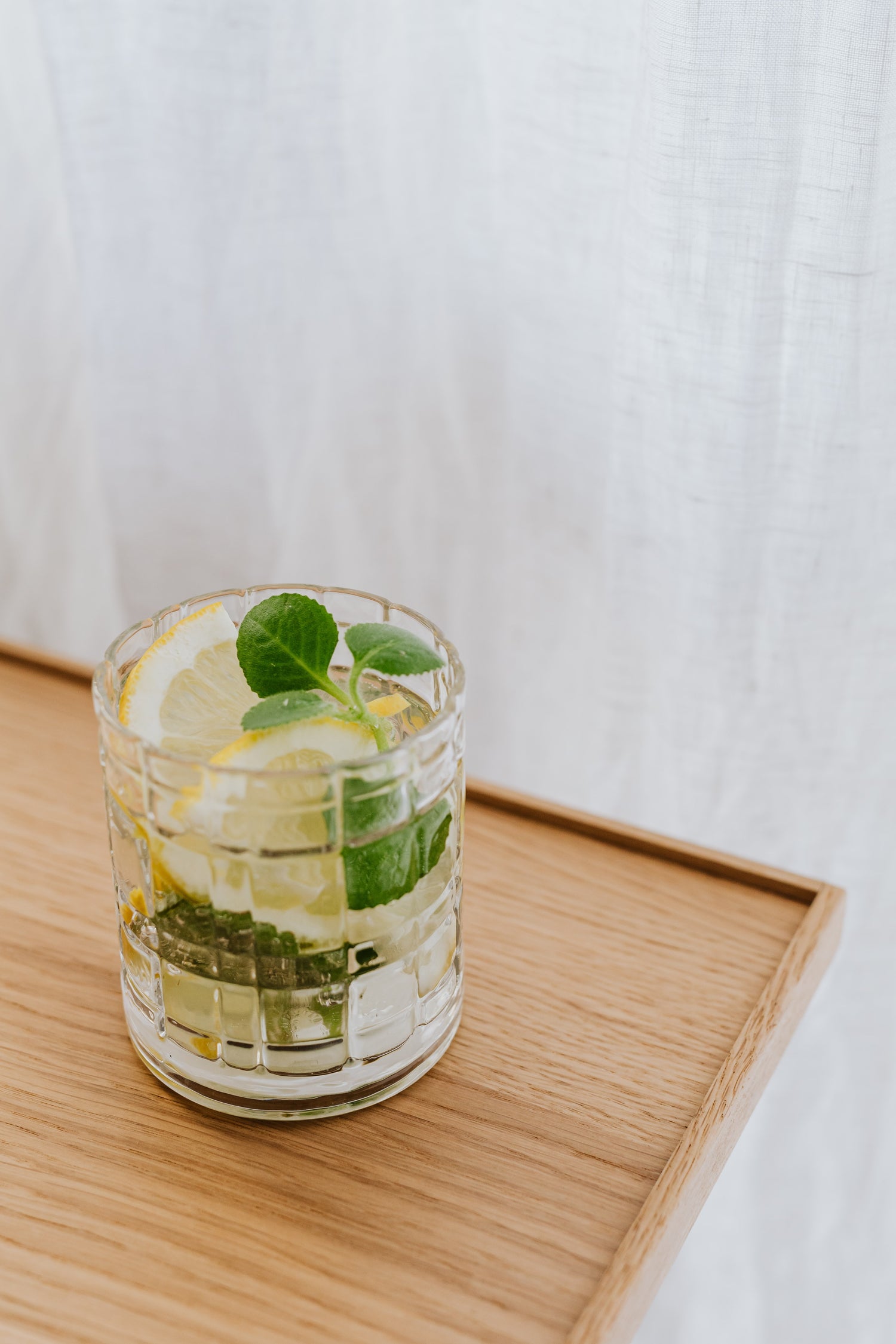 Clear cocktail glass filled with lemon and basil cocktail.